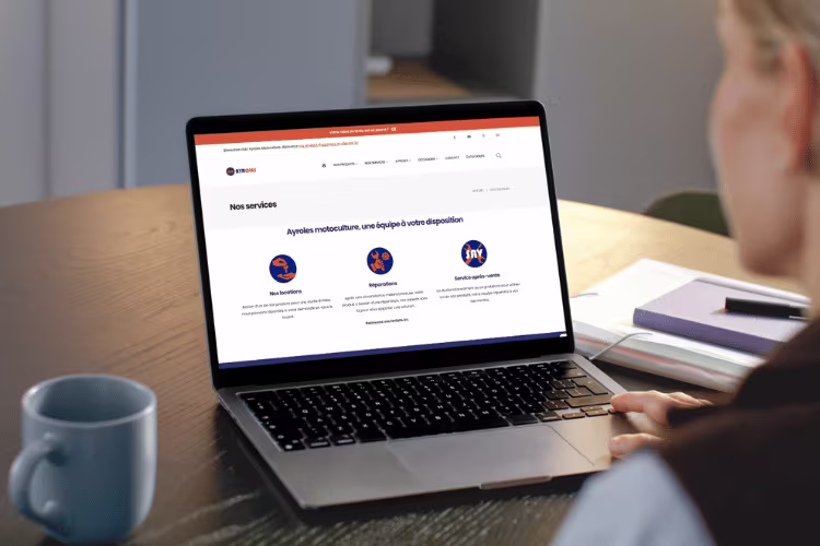 Une personne consulte la page des services d'Ayroles Motoculture afficher sur un MacBook 
